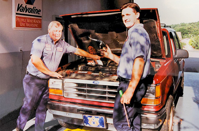 technicians in front of open hood during 1980s